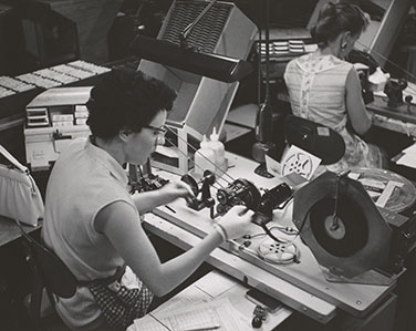 Black and white photograph of two women sitting at desks processing 8mm film (ca. 1955)